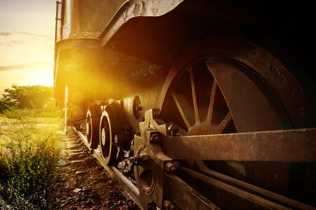 Steam locomotive wheel on the rail with sunlight at sunset backgroundの写真素材