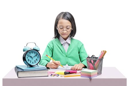 Asian cute girl in glasses learning with school stationary on the desk isolated over white backgroundの写真素材