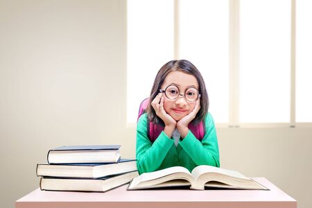 Asian cute girl with glasses and backpack with books on the desk with window backgroundの写真素材