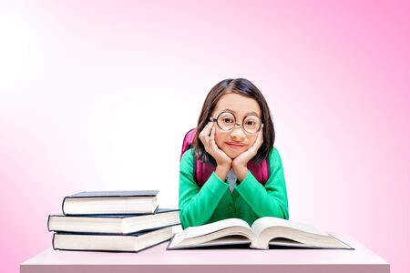Asian cute girl with glasses and backpack with books on the desk over bright backgroundの写真素材