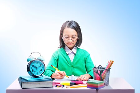 Asian cute girl in glasses learning with school stationary on the desk over bright backgroundの写真素材