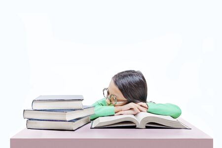 Asian cute girl with glasses fall asleep on book on the desk isolated over white backgroundの写真素材