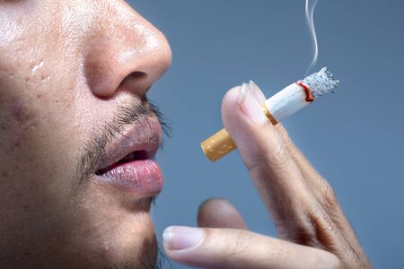 Man smoking cigarette on gray backgroundの写真素材