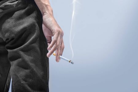 Man standing with a cigarette on his hand over gray background