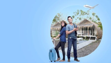 Asian couple with suitcase bag and backpack standing with cottage background and plane on the sky. Traveling conceptの写真素材