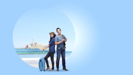 Asian couple with suitcase bag and backpack standing with sandy beach background and ferry boat sailing on the sea. Traveling conceptの写真素材