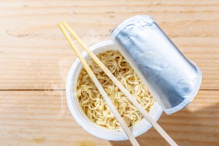 Instant cup noodle with chopstick on wooden tableの写真素材