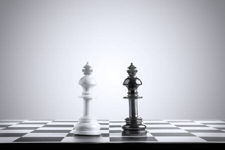 White king chess piece standing face black king chess piece on the chessboardの写真素材