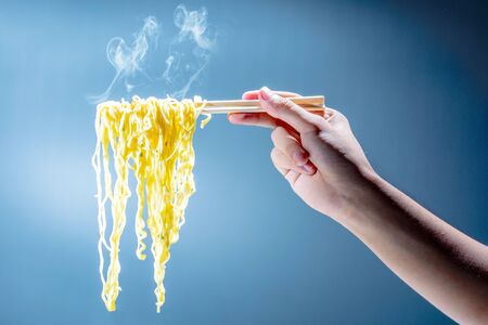 People eat the noodles with chopsticks over bright backgroundの写真素材