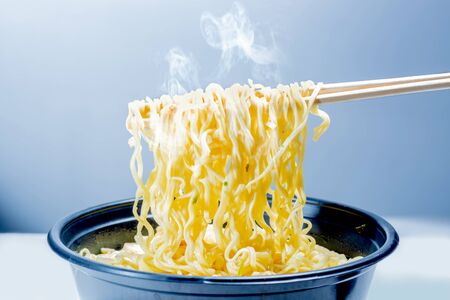 People eat the noodles with chopstick over bright backgroundの写真素材