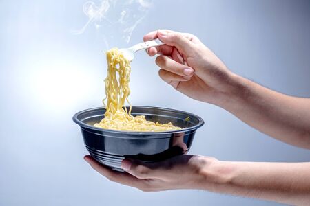 People eat the noodles with fork over bright backgroundの写真素材