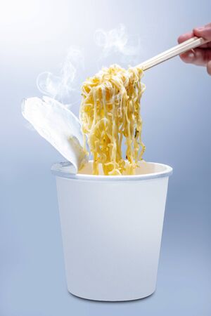 People eat the instant cup noodles with chopstick on bright backgroundの写真素材