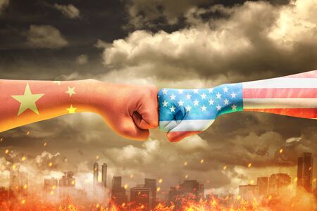 Hands of two men with Chinese skin and American skin bumping their fists over the dramatic background. Trade war Chinese against Americaの写真素材