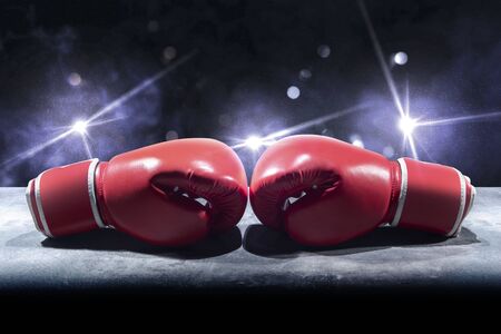 Pair of red boxing gloves on the table over bright lights background