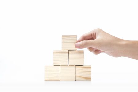 Hand build a pyramid from a wooden block isolated over white background