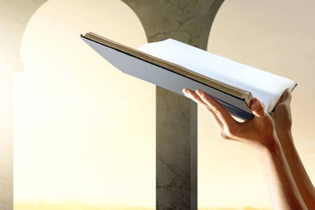 Muslim hands holding Koran open inside the mosqueの写真素材