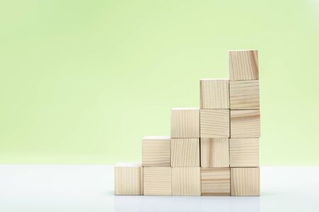Stairs of wooden block toy on the table over green backgroundの写真素材