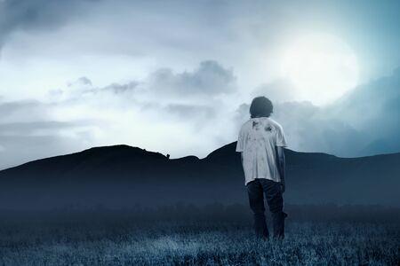 Scary zombies with blood and wound on his body walking around on the grass field with moonlight....