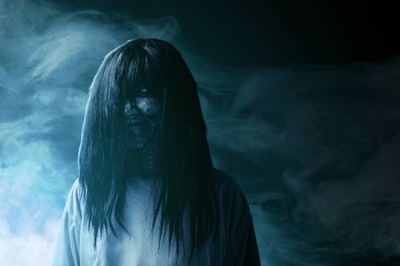 Scary ghost woman with blood and dirty face standing amid the dark fog. Halloween conceptの写真素材