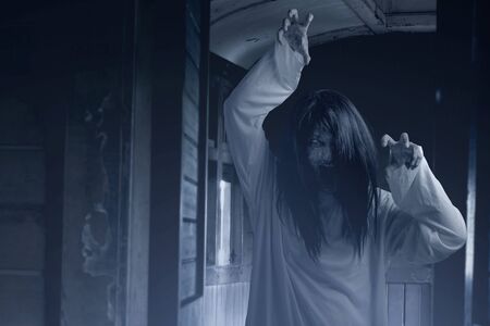Scary ghost woman with blood and angry face with clawing hands on the old wagon. Halloween concept