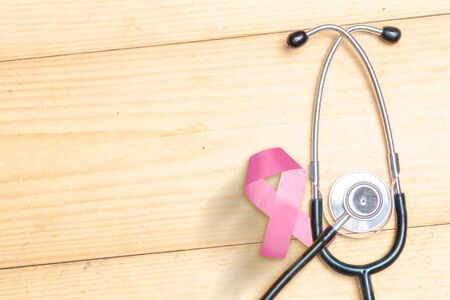 Pink awareness ribbon and stethoscope on a wooden background. Breast cancer awarenessの写真素材