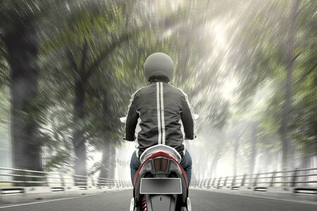 Rear view of Asian motorcycle taxi man driving on the asphalt roadの写真素材