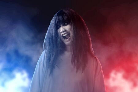 Scary ghost woman with blood and dirty face standing amid the dark fog. Halloween concept