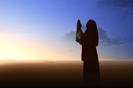 Jesus Christ raised hands and praying to god with a sunset sky backgroundの写真素材