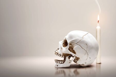 Candle and human skull over gray backgroundの写真素材