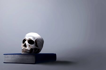 Book with a human skull over black background