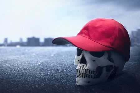 Human skull wearing a red hat on the urban street with the night scene backgroundの写真素材