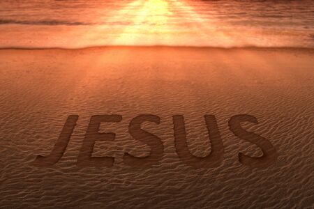 Jesus text on the sandy beach with a sunset sky backgroundの写真素材
