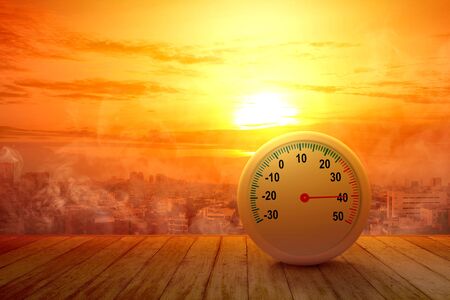 The thermometer on a wooden table with a high temperature on the city with a glowing sun background. Heatwave conceptの写真素材