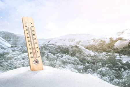 The thermometer on the snow measuring the temperature outdoor with a clear sky background. Heatwave conceptの写真素材