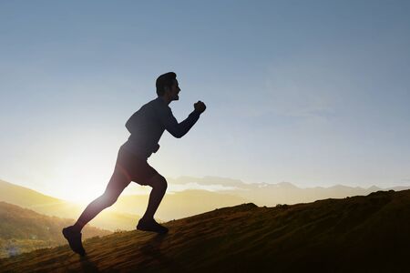Asian runner man running on the mountain with a blue sky background