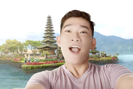 Asian man making selfie using the camera phone with Ulun Danu Temple backgroundの写真素材