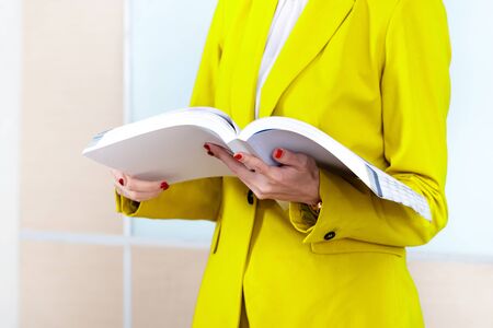 Businesswoman standing while holding the book on the workplace