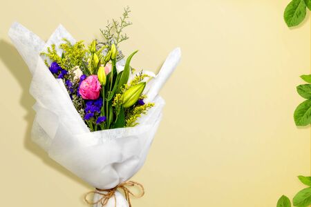 Flower bouquet wrapped in paper with vibrant color on a colored backgroundの写真素材