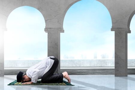 Asian Muslim man with a prayer rug in a praying position (salat) inside the mosqueの写真素材