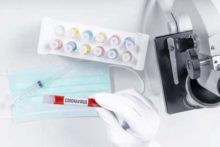 Doctor man in protective gloves holding a test tube with a coronavirus blood sample. Prevent flu...