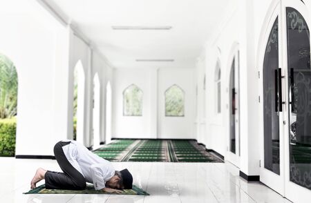Asian Muslim man with a prayer rug in a praying position (salat) inside the mosqueの写真素材