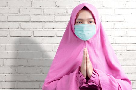 Asian Muslim woman in a veil and wearing flu mask praying in the home. Prevent the spread flu disease Coronavirusの写真素材