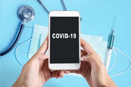 Hands holding a mobile phone with COVID-19 text on the screen. Prevent flu disease Coronavirusの写真素材