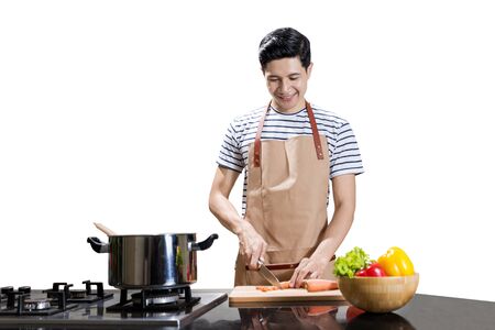 Asian man cutting vegetables with a knife on cutting board isolated over white backgroundの写真素材
