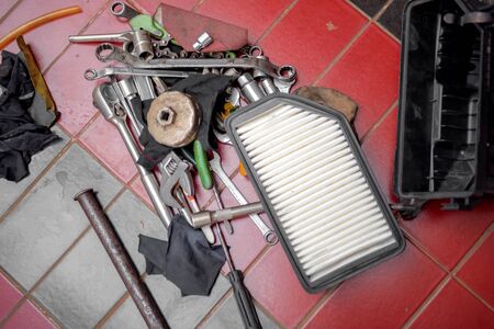 Car mechanic tools and air filter on the garage floor