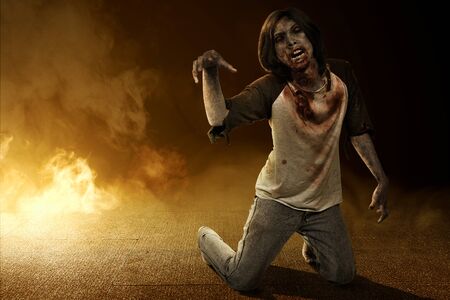 Scary zombie with blood and wound on his body crawling on the floor with smoke background