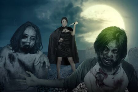 Asian witch woman and scary zombies with blood and wound on his body walking around on the graveyardの写真素材