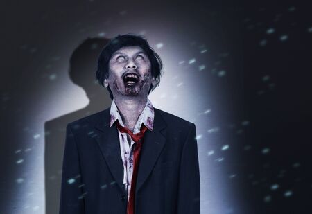 Scary zombie with blood and wound on his body standing on the dark room