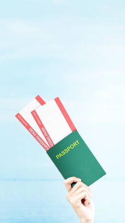 Hand holding ticket and passport with a blue sky background. Stories templateの写真素材