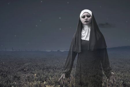 Frightening devil nun on the meadow. Halloween conceptの写真素材